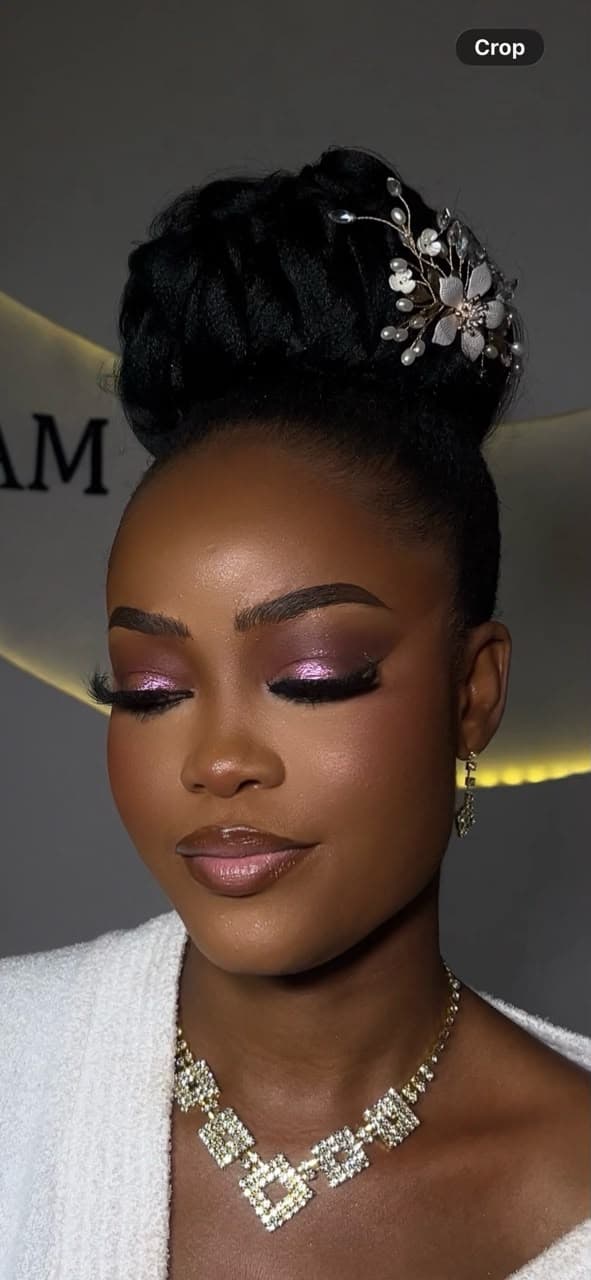 Bride with elegant black updo, floral hair pin and glam makeup at Hairxpresser.NG